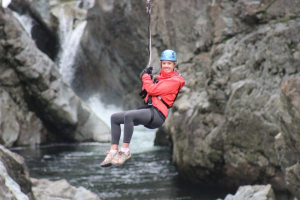 Woman hanging over a river while on a zip-line