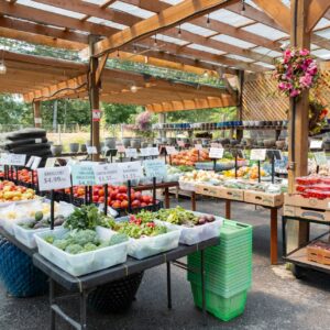 Bins of colorful fruits, vegetables, and plants under a covered outdoor stand at Naesgaard’s Farm & Market.
