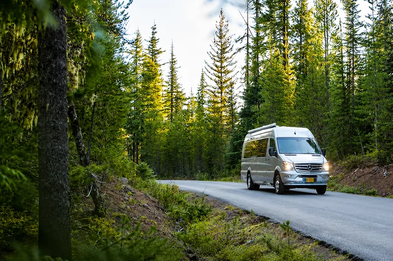 Camper van driving through a forest on Vancouver Island
