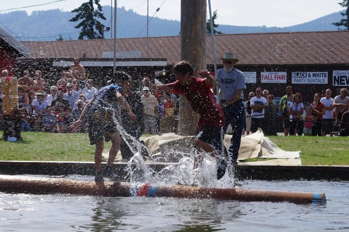 Competitors take part in Log Rolling at the Alberni District Fall Fair as spectators watch from the sidelines.