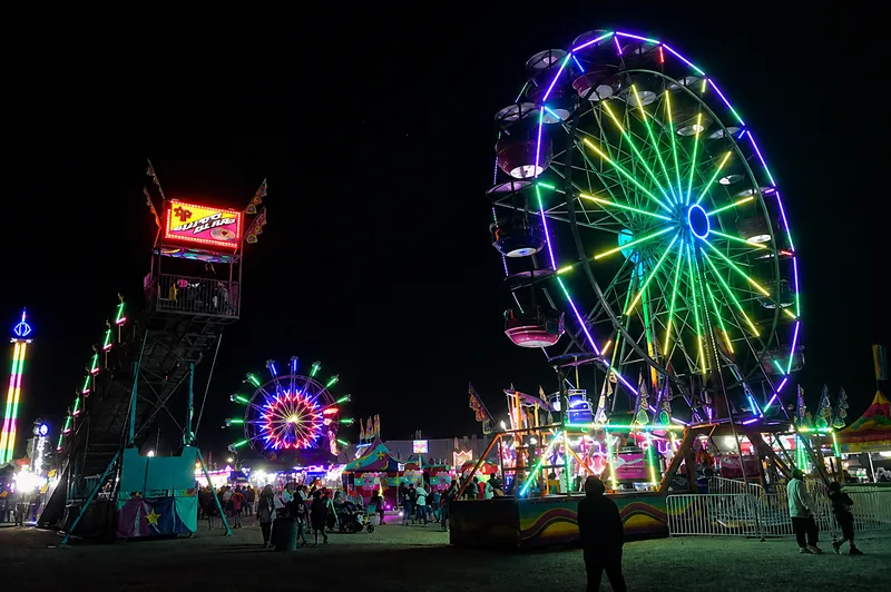 Ferris wheel and midway rides illuminated at night during the Alberni District Fall Fair.