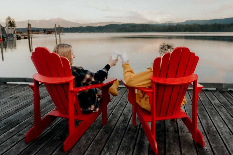 Couple sitting in red chairs on a dock overlooking the water in Port Alberni during winter
