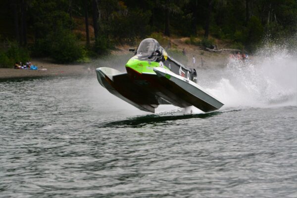 Modern Formula One hydroplane creating a spray of water as it speeds across Sproat Lake.