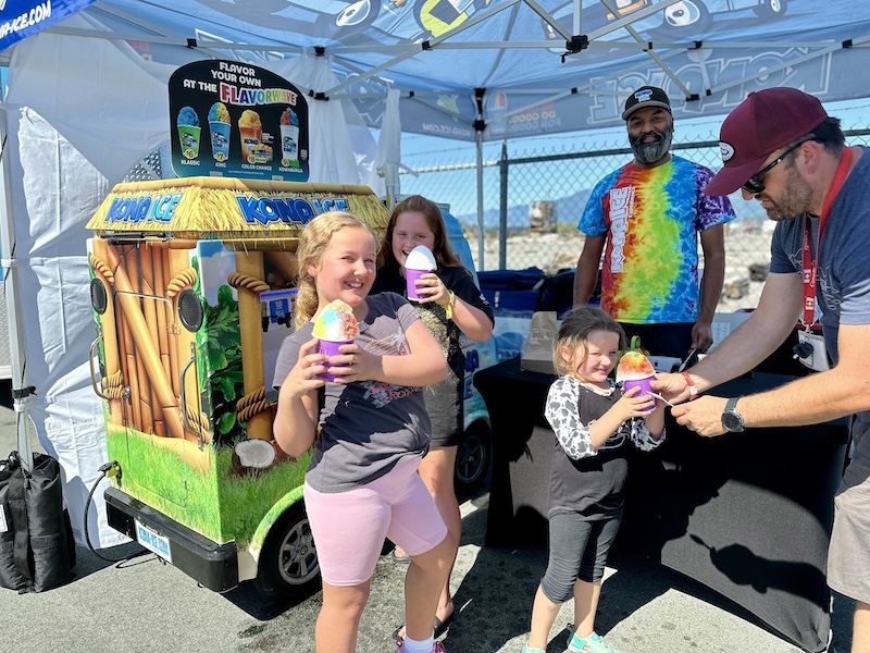 Smiling kids enjoy rainbow Kona Ice treats at an outdoor booth during Port Alberni Salmon Festival.