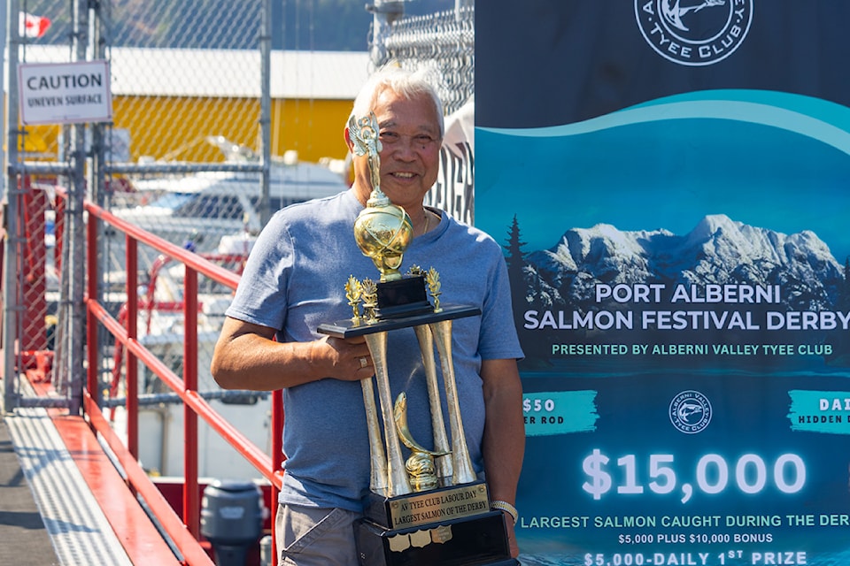 Don Kimura holding the 2025 Port Alberni Salmon Festival Derby trophy after winning with a 30-pound chinook, standing beside a banner promoting the $15,000 grand prize.