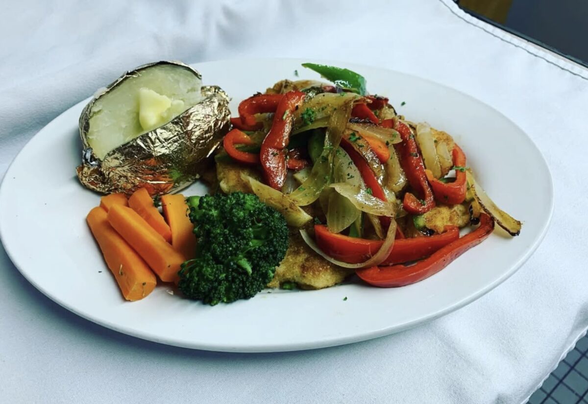 Paprika schnitzel from Little Bavaria Restaurant in Port Alberni, topped with sautéed onions and bell peppers, served with steamed vegetables and a baked potato wrapped in foil.
