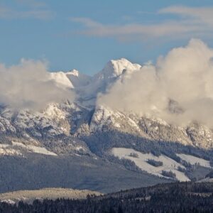 Mount Arrowsmith rising above the Alberni Valley with snow-covered alpine peaks and drifting clouds, viewed from the Somass Estuary.