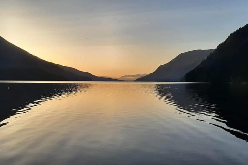 Sunset over Sproat Lake with mountains reflected in calm water