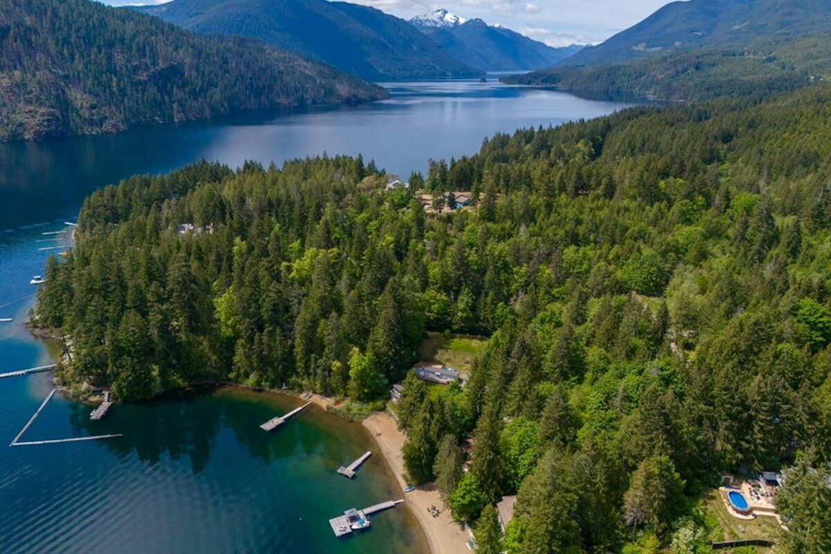 Aerial view of Sproat Lake shoreline with forest, docks, and small beach access points