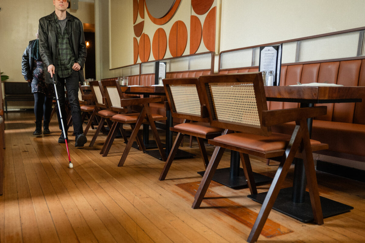 Restaurant interior with hardwood floors, wide clear pathways, and table seating throughout the space.