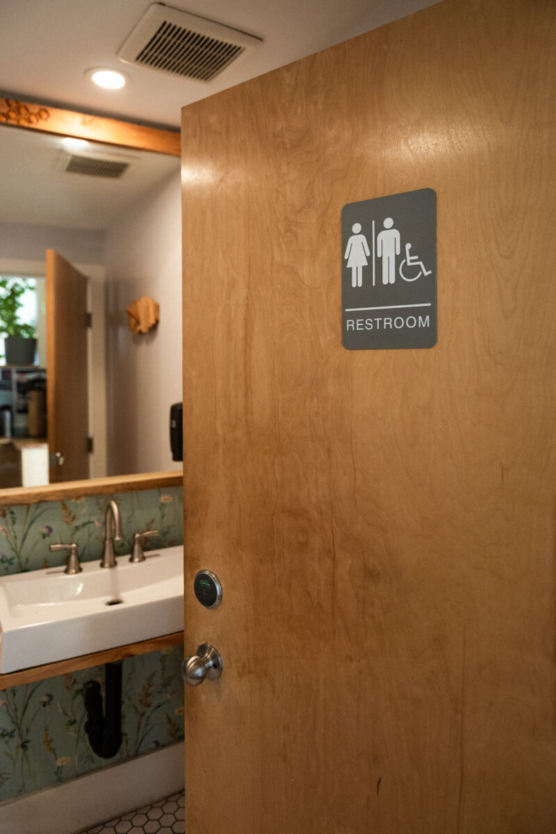 This single-user washroom features installed grab bars, ample space to move, and a sink designed for wheelchair roll-under access.