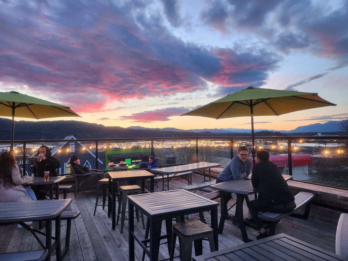 Guests enjoying sunset views from the Dog Mountain Brewing patio overlooking the Alberni Inlet in Port Alberni.