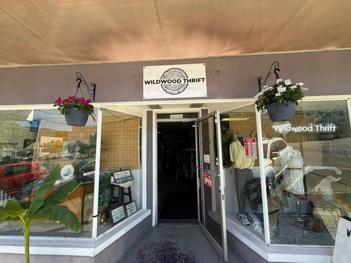 Front entrance of Wildwood Thrift in Port Alberni, featuring large display windows, hanging flower baskets, and a welcoming storefront with clothing and home décor on display.