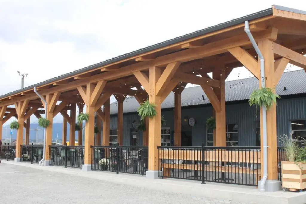 A wide scenic shot of the freshly renovated Harbour Quay waterfront in Port Alberni under a blue sky, showcasing new architectural details and vibrant community gathering spaces.